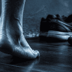 varus du pied vu de dos sur parquet sombre